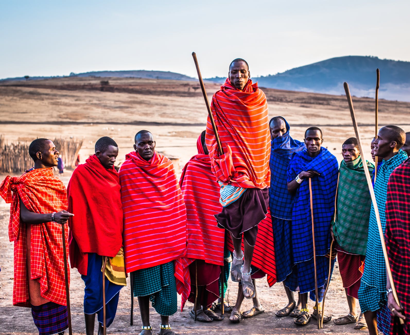 photo of group of men wearing assorted scarves holding sticks